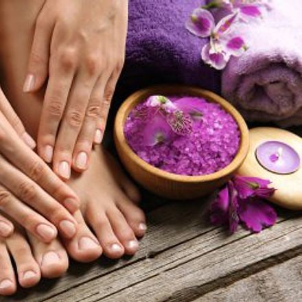 Manicure and pedicure – groomed hands and feet by a bowl of lavender salt